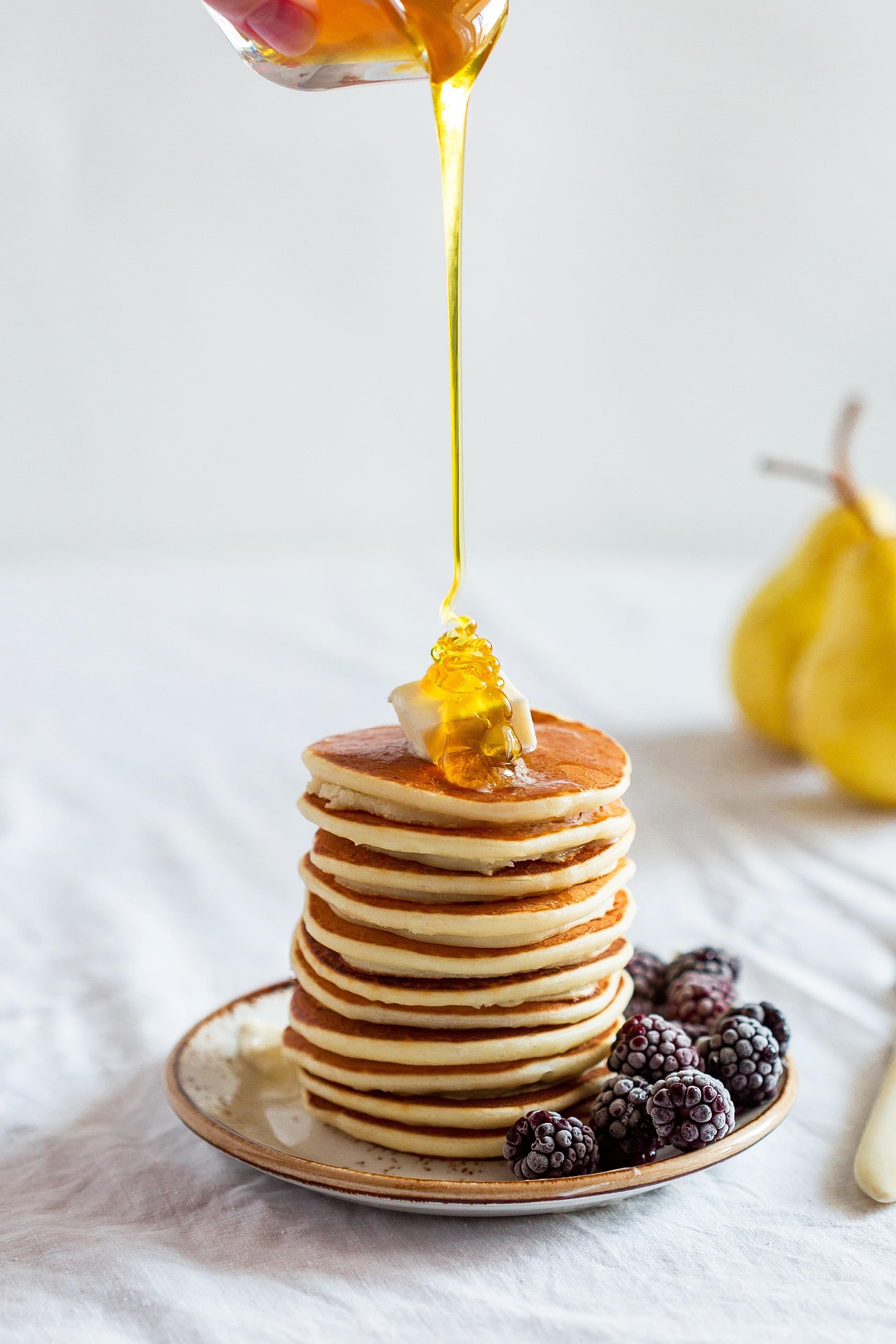 Honig wird über Pancakes gegossen