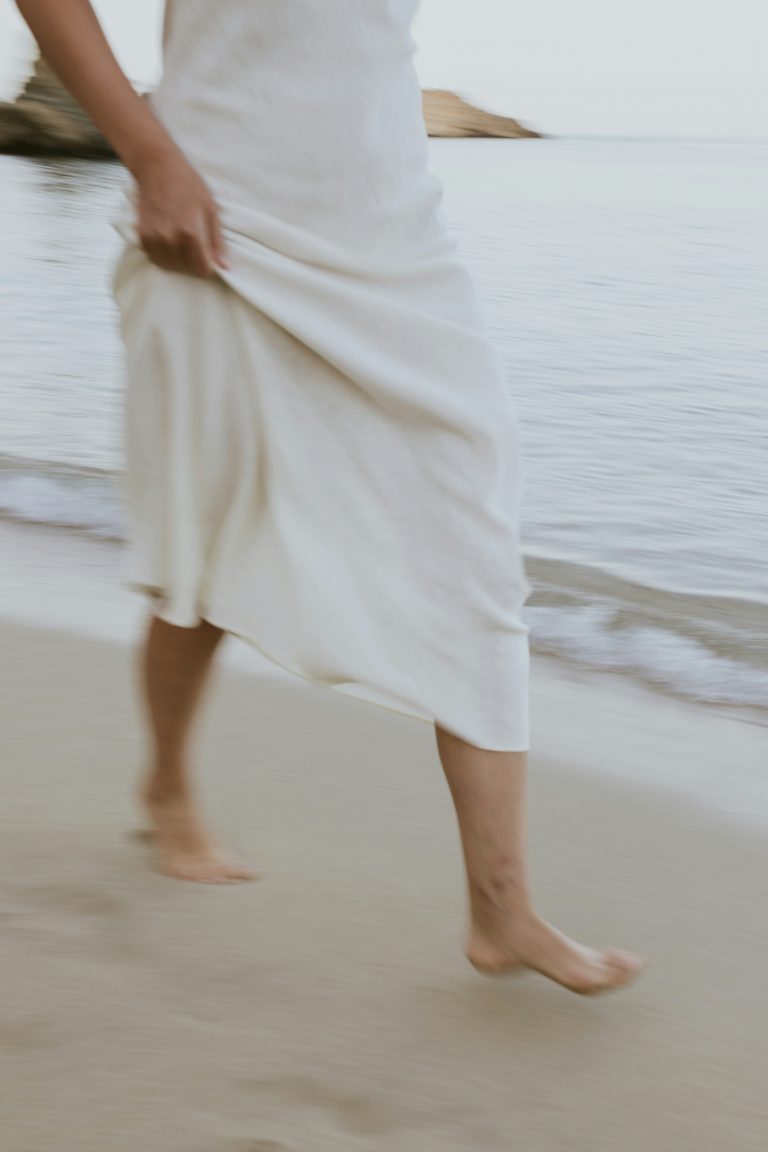 Frau barfuß am Meer, Sinnbild für Vertrauen auf festen Grund in Gottes Führung